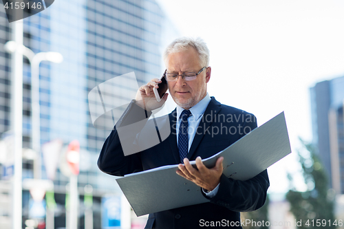 Image of senior businessman calling on smartphone in city