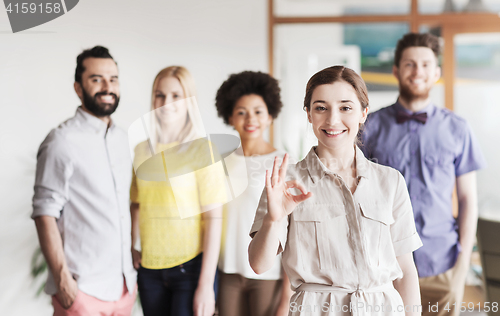 Image of happy woman showing ok over creative office team