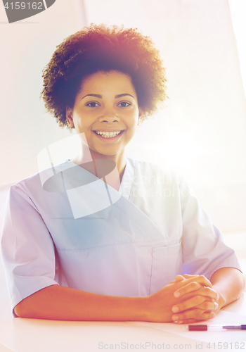 Image of happy doctor or nurse with clipboard at hospital