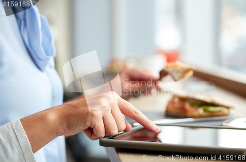 Image of woman with tablet pc and panini sandwich at cafe