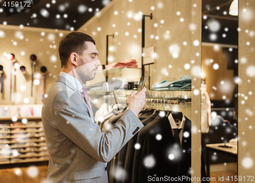 Image of man in suit with smartphone at clothing store