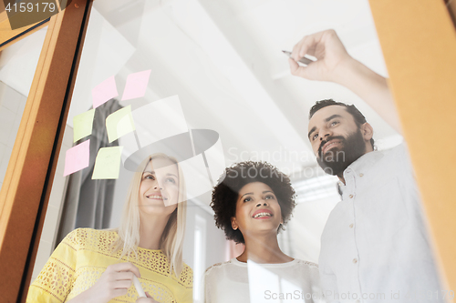 Image of happy creative team writing on stickers at office