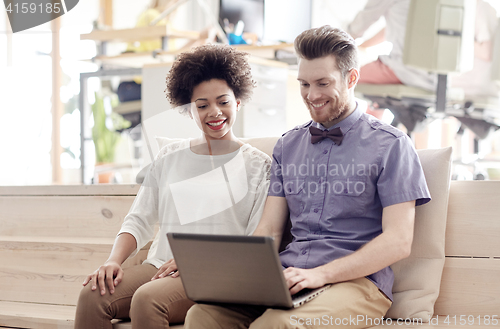 Image of happy creative team with laptop in office