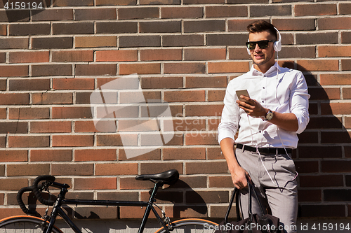 Image of man with headphones, smartphone and bicycle