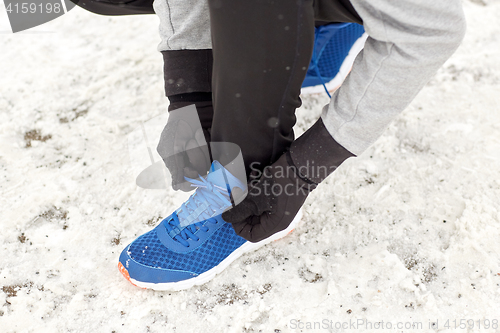 Image of close up of man tying shoe lace in winter outdoors