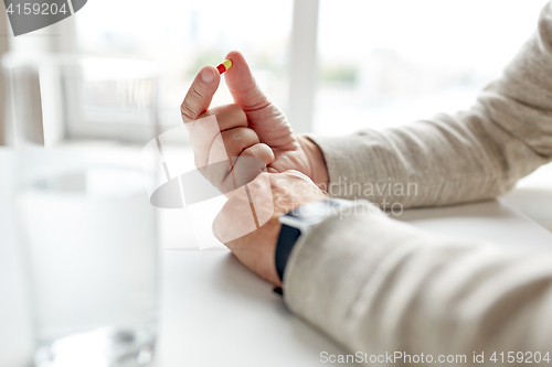 Image of close up of old man hands with pill