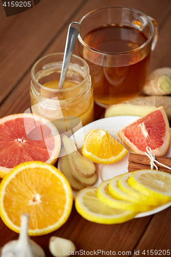 Image of ginger tea with honey, citrus and garlic on wood