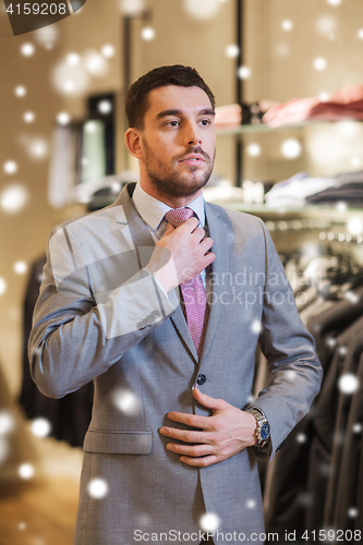 Image of young man trying suit on in clothing store