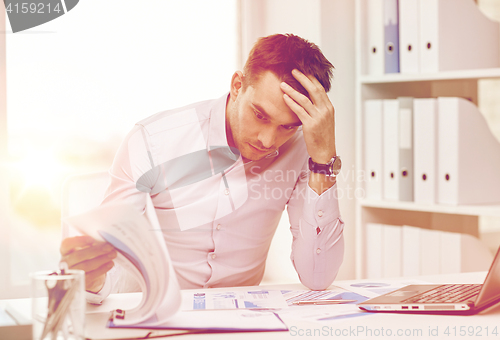 Image of stressed businessman with papers at office
