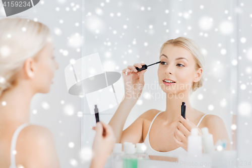 Image of woman with mascara applying make up at bathroom