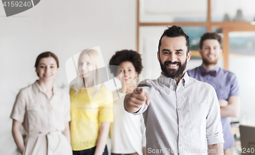Image of happy man pointing finger at you over office team