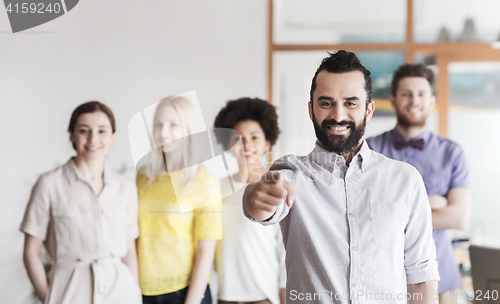 Image of happy man pointing finger at you over office team