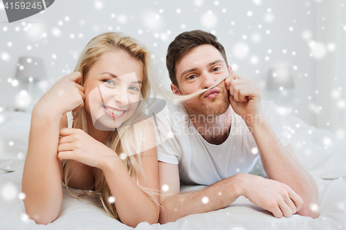 Image of happy couple lying in bed at home