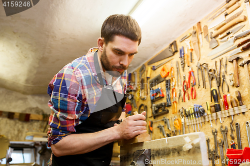 Image of carpenter working with plane and wood at workshop