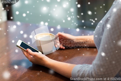 Image of woman with smartphone drinking coffee at cafe