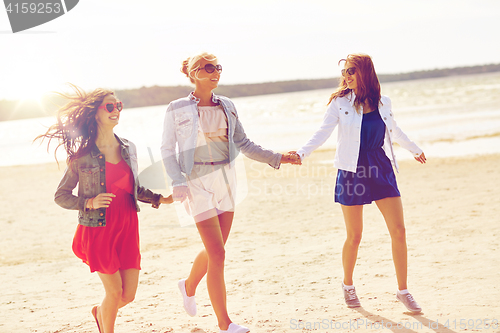 Image of group of smiling women in sunglasses on beach