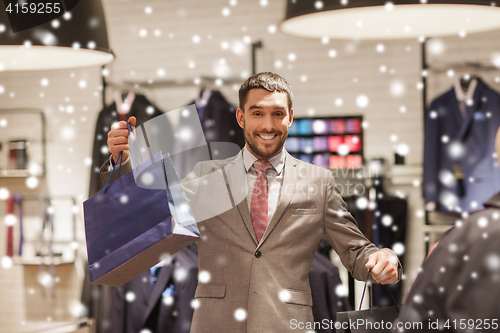 Image of happy man with shopping bags at clothing store