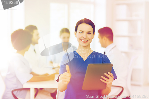 Image of happy doctor with tablet pc over team at clinic