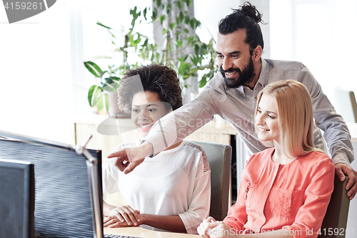 Image of happy creative team with computer in office