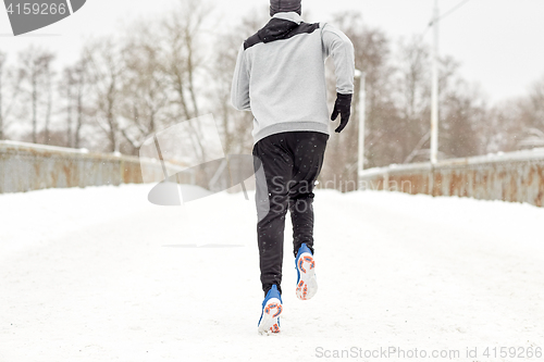 Image of man running along snow covered winter bridge road
