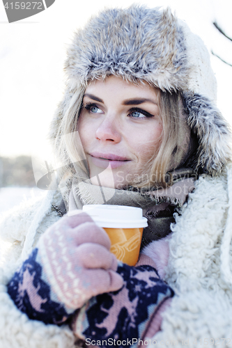 Image of young pretty teenage hipster girl outdoor in winter snow park having fun drinking coffee, warming up happy smiling, lifestyle people concept