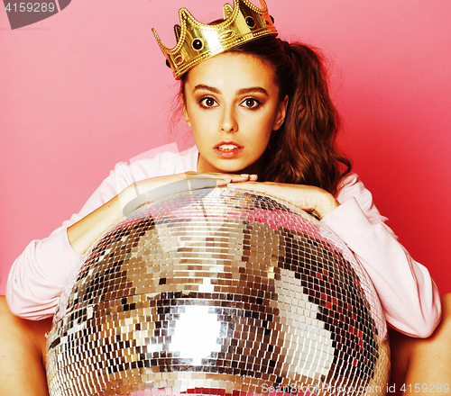 Image of young cute disco girl on pink background with disco ball and cro