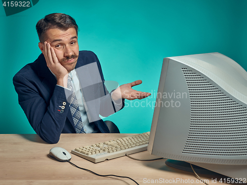 Image of Sad Young Man Working On computer At Desk