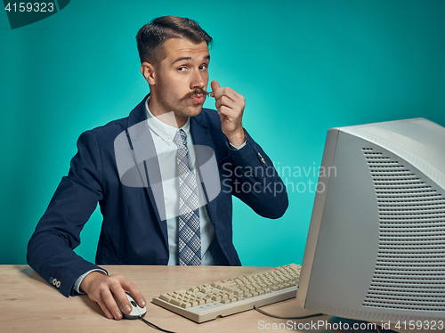 Image of Portrait of cheerful young businessman sitting with computer