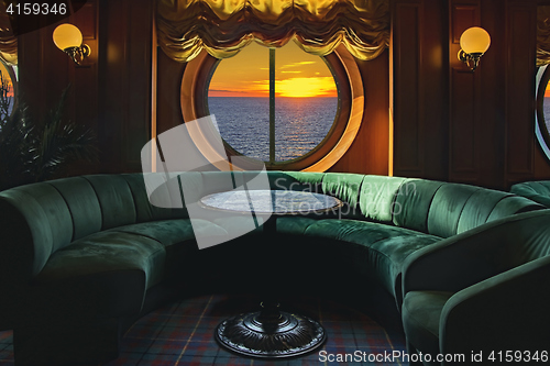 Image of Lounge on a cruise ship, with tables and armchair in the sunset