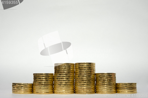 Image of Six stacks of coins increasing height symmetrically on a white background, pockmarked stands on the edge of the Russian 10 ruble coin