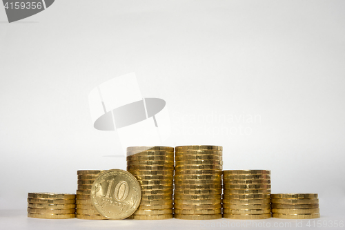 Image of Six stacks of coins increasing height symmetrically on a white background, pockmarked stands on the edge of the Russian 10 ruble coin