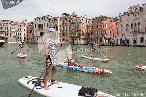 Image of Group of active tourists stand up paddling on sup boards at Grand Canal, Venice, Italy.