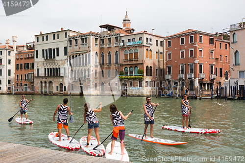 Image of Group of active tourists stand up paddling on sup boards at Grand Canal, Venice, Italy.