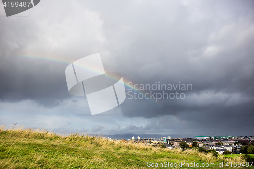 Image of cloudy sky and rainbow above the city