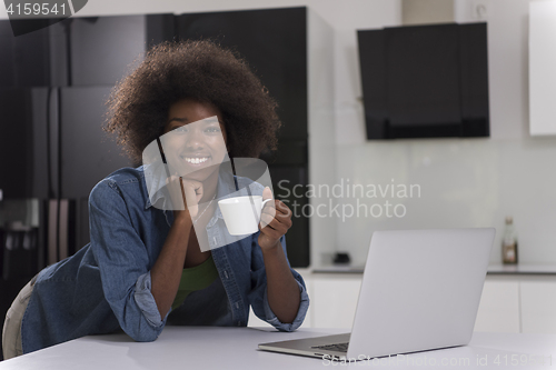 Image of smiling black woman in modern kitchen