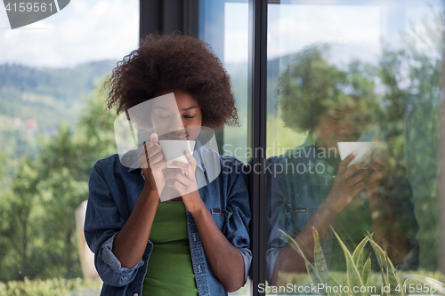 Image of African American woman drinking coffee looking out the window