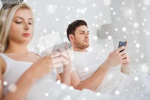 Image of couple with smartphones in bed