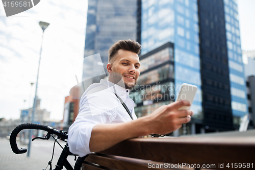 Image of happy man with smartphone and bicycle in city