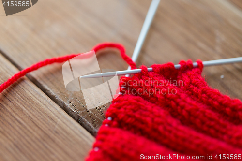 Image of hand-knitted item with knitting needles on wood