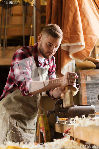 Image of carpenter working with plane and wood at workshop