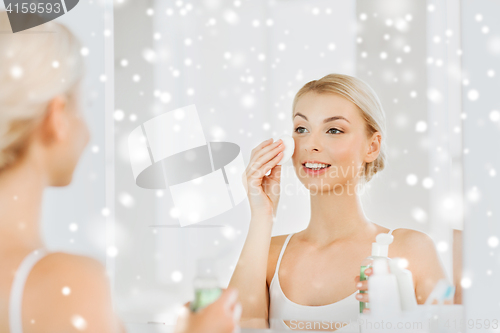 Image of young woman with lotion washing face at bathroom