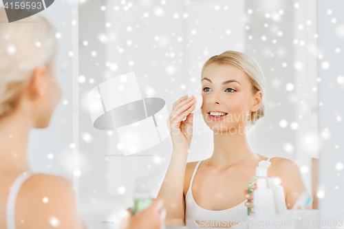 Image of young woman with lotion washing face at bathroom