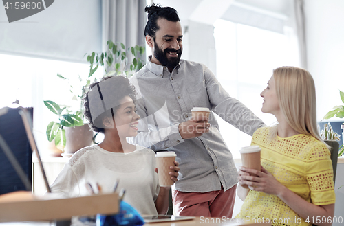 Image of happy creative team drinking coffee in office