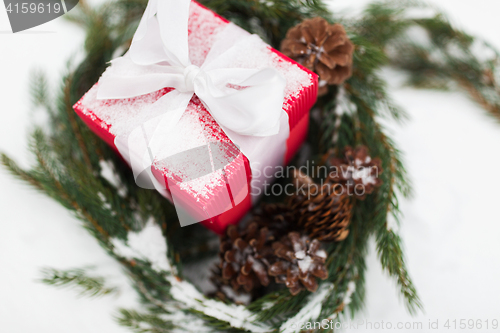 Image of close up of christmas gift and fir wreath on snow