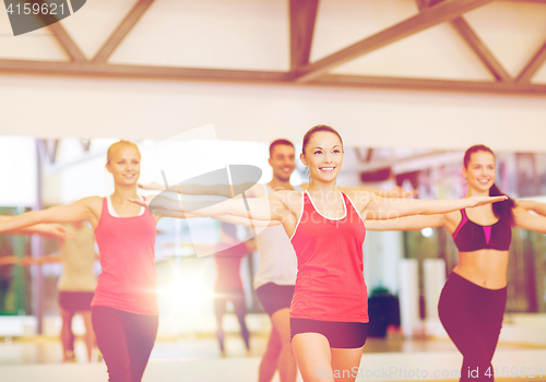 Image of group of smiling people exercising in the gym