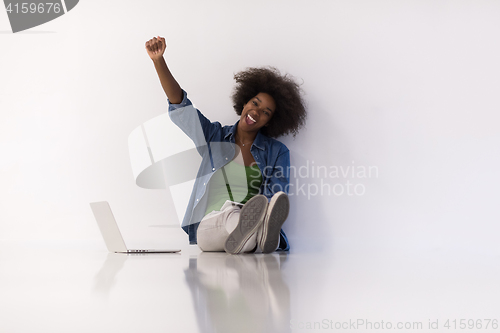 Image of african american woman sitting on floor with laptop