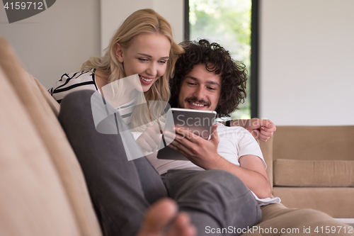 Image of couple relaxing at  home with tablet computers