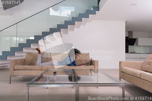 Image of African American woman using laptop on sofa