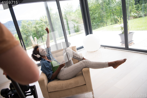 Image of African american woman at home in chair with tablet and head pho