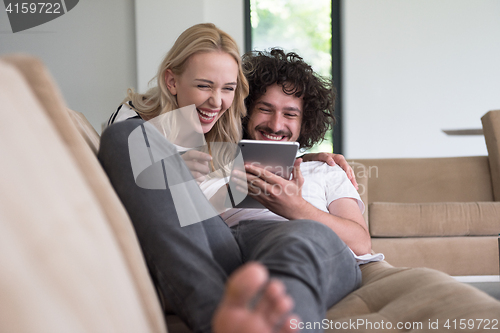 Image of couple relaxing at  home with tablet computers